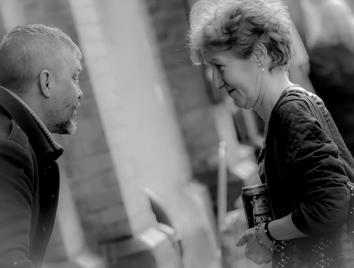 Man and woman leaning toward each other in conversation on a city sidewalk